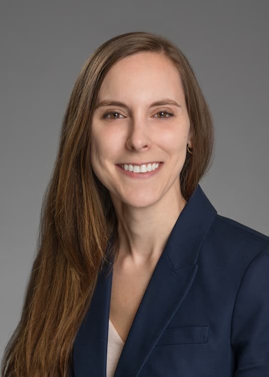 Headshot of Abigail Whitaker wearing a navy blazer against a gray background.