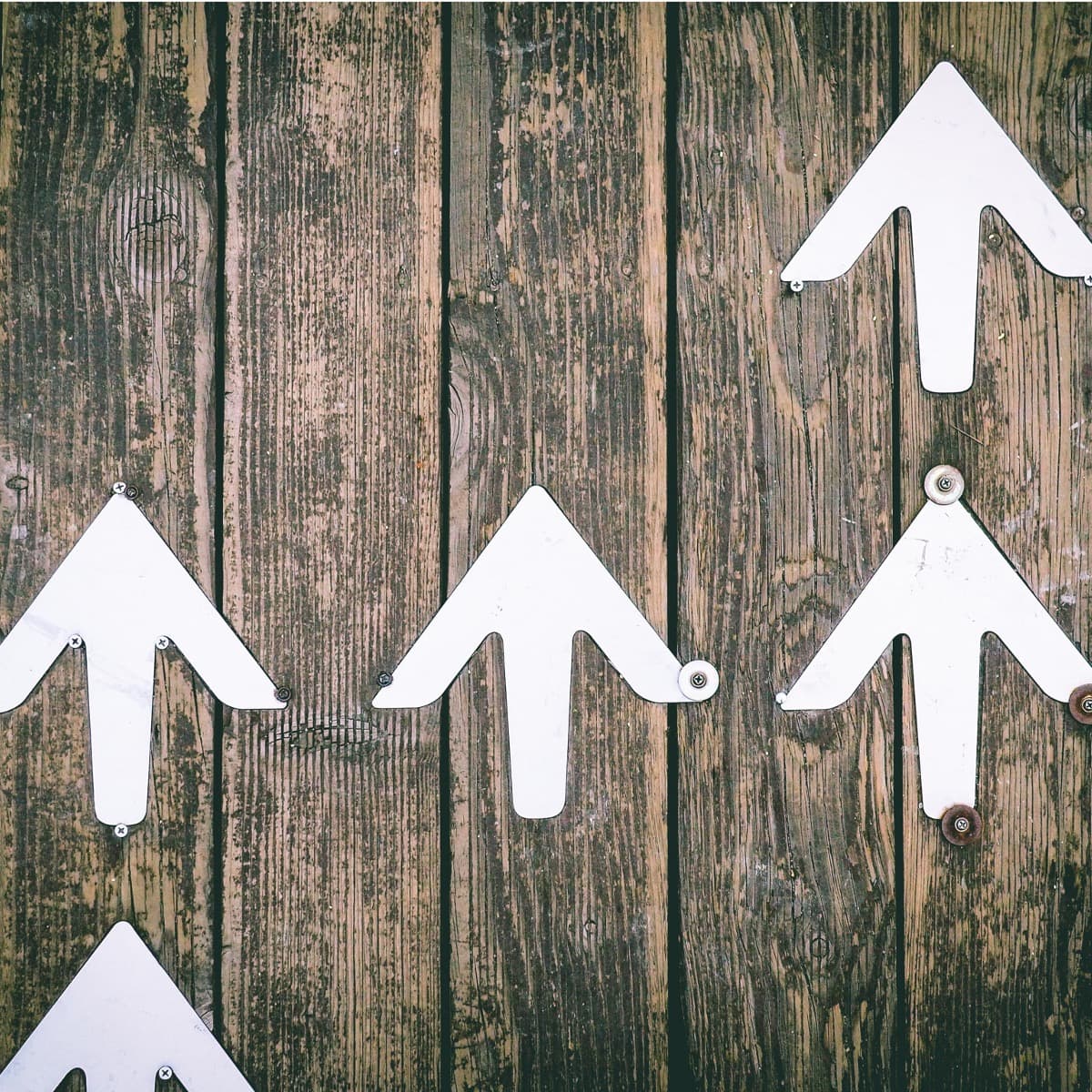 5 white arrows pinned to wooden boards. All arrows pointing up.