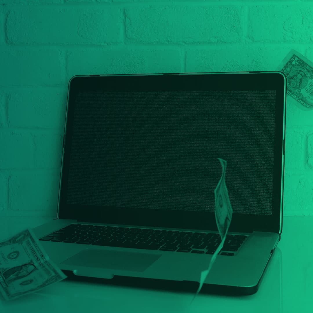 Laptop with dollar bills around it. Image has a green overlay.