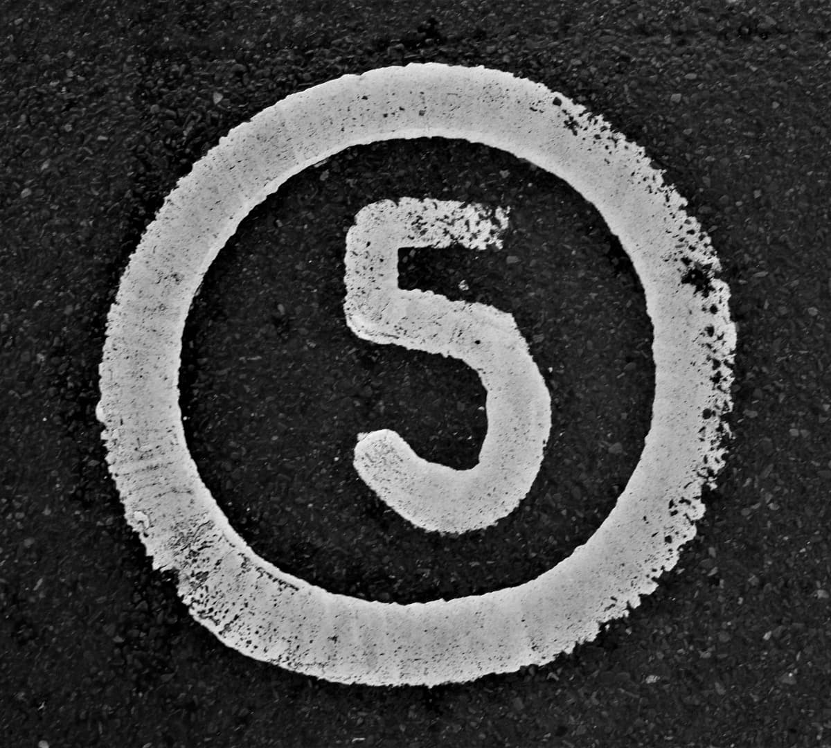 Image of a paved road with the number five and a circle around it painted in white.
